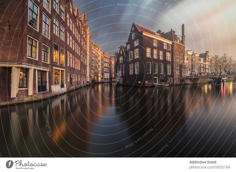 Sunset casts a warm glow on the tranquil Amsterdam canals, with historic Dutch buildings reflected in the water sunset reflection Netherlands architecture