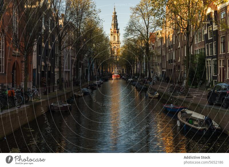 Warm sunset light on Amsterdam canal with moored boats and traditional Dutch houses Netherlands architecture reflection water cityscape urban travel heritage