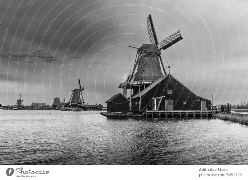 Black and white image of iconic windmills by the water in the historic village of Zaanse Schans, Netherlands black and white Dutch architecture monochrome