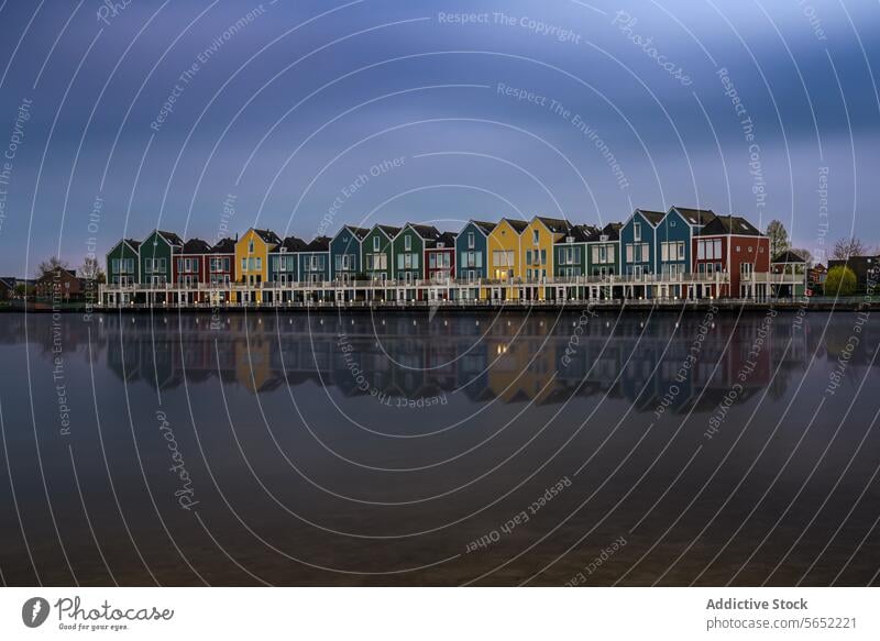 Colorful row houses with reflections on the calm waters of Houten's Rietplas at dusk colorful Dutch Netherlands residential architecture waterfront building