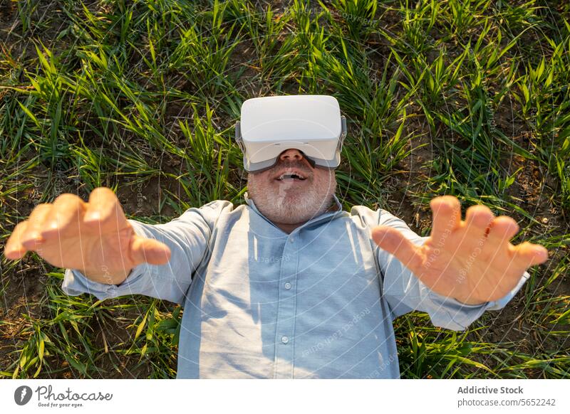 Cheerful senior man using VR glasses on grass during sunny day Man Glasses Senior Grass Innovation Futuristic Happy Lying Technology Lifestyle Leisure