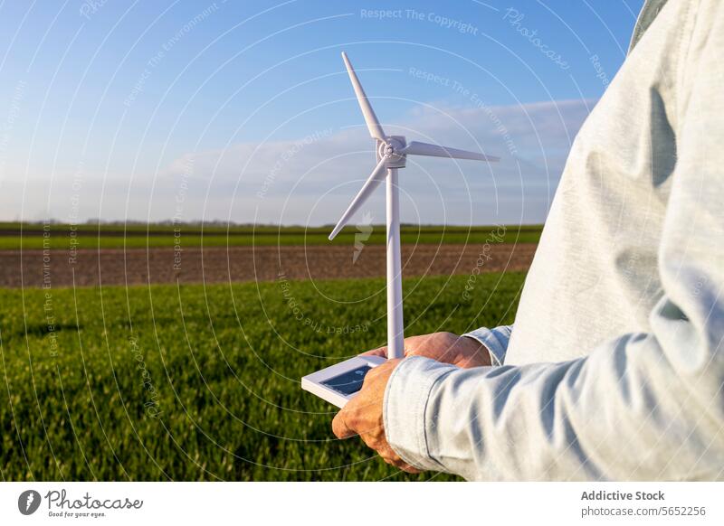 Man holding wind turbine model on agricultural field against blue sky Windmill Model Blue Sky Innovation Futuristic Stand Renewable Energy Technology Lifestyle