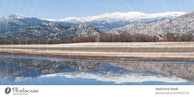 A panoramic view of a serene lake with snow-capped mountains in the background and a clear reflection in the water panorama serenity sky outdoor nature scenic