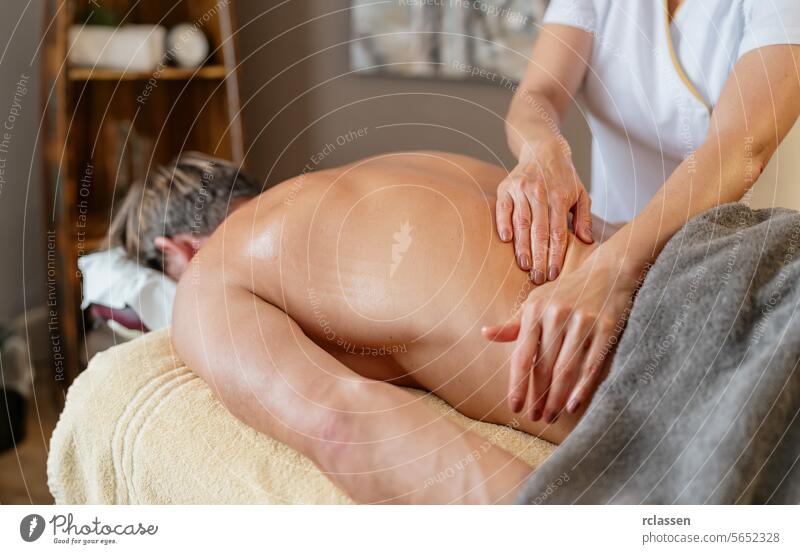 Massage therapist performing back massage on male client in spa. Wellness Hotel Concept image man hotel resort massage oils physiotherapist clinic asian