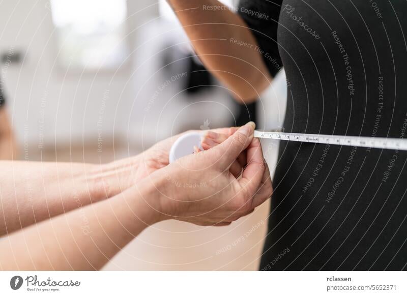 Close-up of a fitness trainer measuring a woman's waist with a tape measure in a gym. Fitness and health concept image slim diet weight loss precision fitting