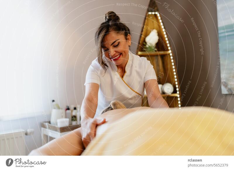 Joyful asian massage therapist applying back massage in a cozy spa beauty salon Wellness Hotel hotel relaxation wellness joy smiling therapy woman masseuse