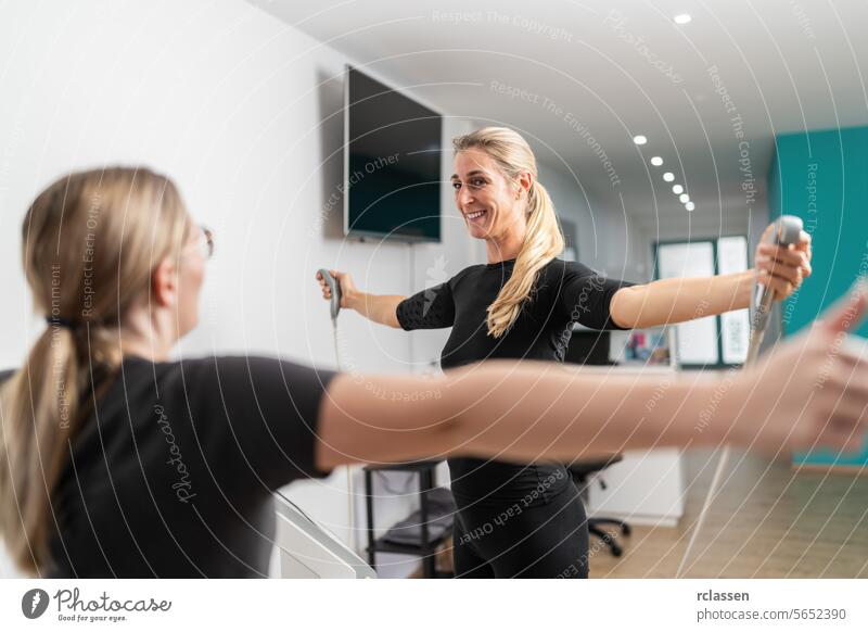 fitness client smiling while holding body composition scale analyzer handles Inbody test, extending arms towards the trainer in a EMS - Studio. inbody fat