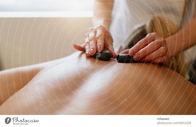 Close-up of a hot stone massage on a person’s back with therapist's hands. Wellness Hotel Concept image hotel asian beauty salon pressure point back massage