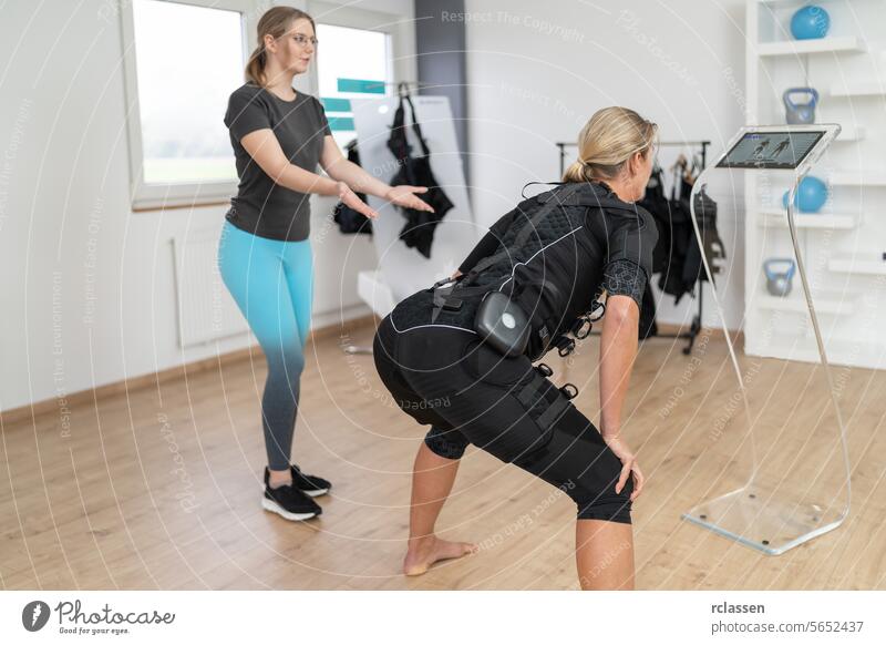 Woman in EMS suit performing exercises with personaö trainer guidance in a EMS-Studio electro stimulation neuromuscular electrical body sculpting