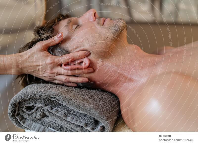 Close-up of a man getting an ear and neck massage at a spa resort hotel ear massage head massage male patient therapist wellness stress relief body care