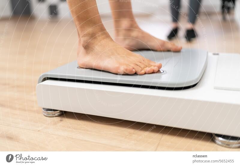 Close-up of bare feet stepping onto a modern body composition scale in a fitness or medical setting during Inbody test analyzing bioelectric technology computer