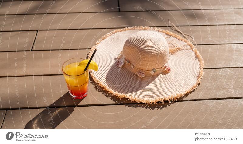 Summer cocktail with straw hat on a wooden deck, symbolizing relaxation and vacation vibes party caribbean island hotel fruit garnish sunny holiday drink summer