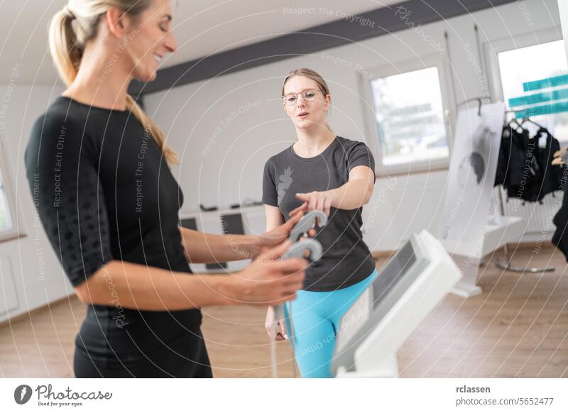 Trainer explaining body composition scale for Inbody analysis test  client holding handles in a fitness studio, both looking engaged. analyzing bioelectric