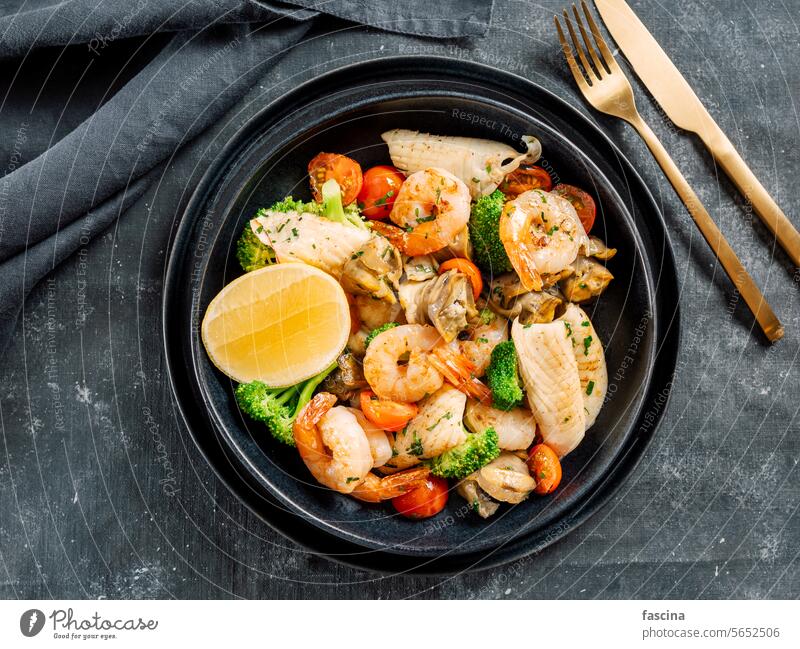 Salad with Mixed Seafood on dark plate seafood platter salad mixed contain shrimps mussels seafood dish calamari squids fish broccoli restaurant cherry tomato
