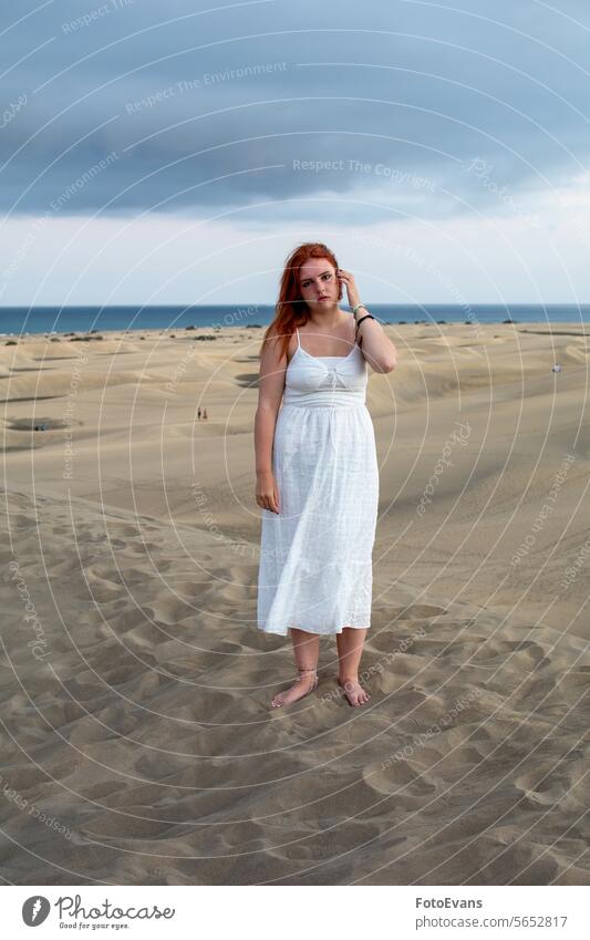 Young woman stands in the sand dunes portrait cute dress European young beauty female attractive beach sandy beach outdoors summer time white teenager desert