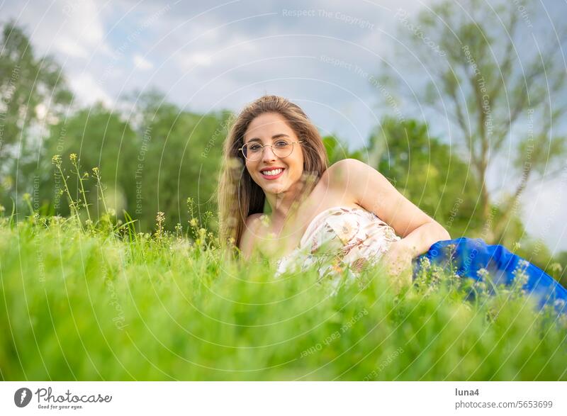 happy young woman with glasses lying on a meadow Woman fortunate youthful Laughter pretty Single cheerful portrait Attractive optimistic relaxed Joy