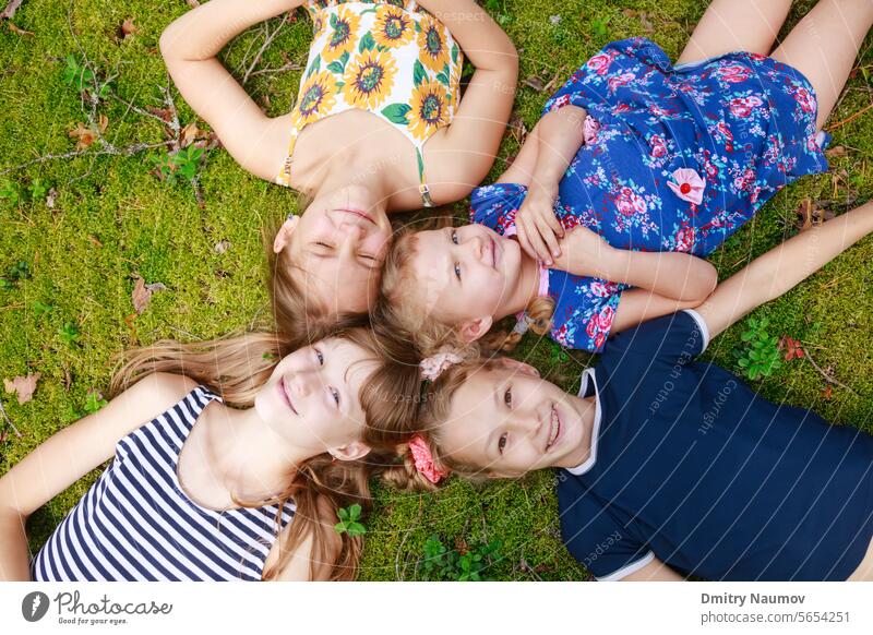 Girls of different age lying together on a moss in a summer forest enjoying summer holidays outdoor above camping candid carefree cheerful child childhood