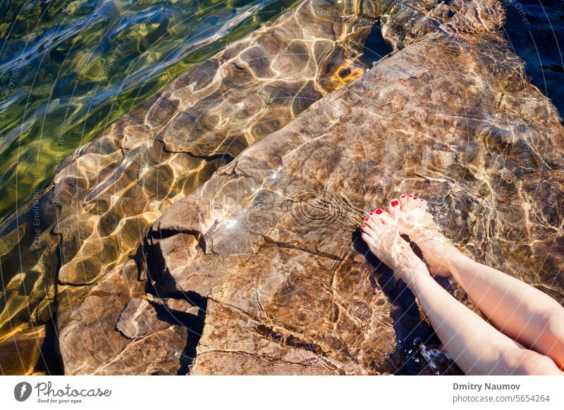 Woman dipping her feet in a crystal clear water of a lake in Norway adult bare barefoot beach clean cool ecology enjoy enjoyment environment fiord fjord girl