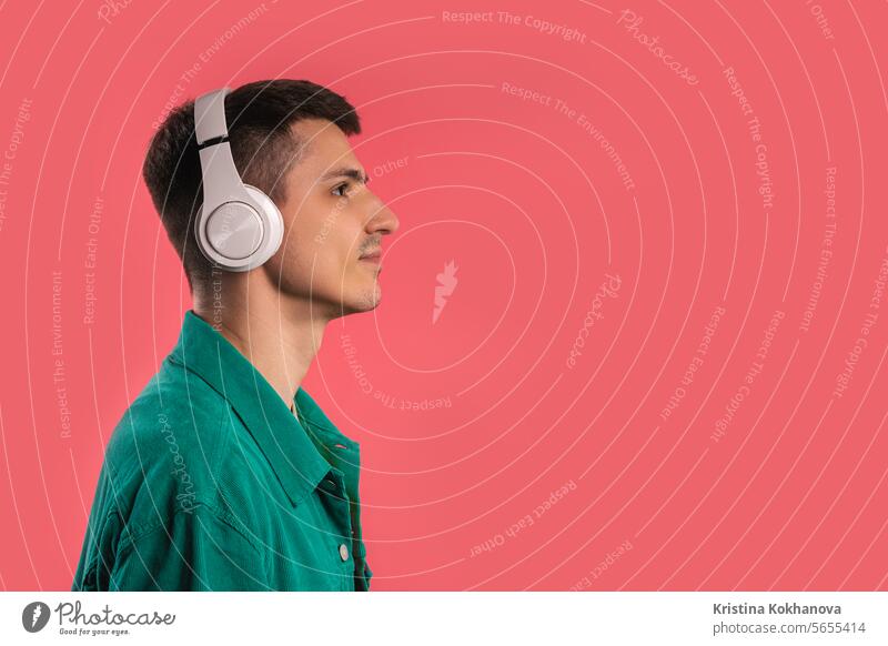 Positive man listening music, enjoying dance with headphones on pink studio active adult beat casual colorful curly dancing earphones energy enjoying song