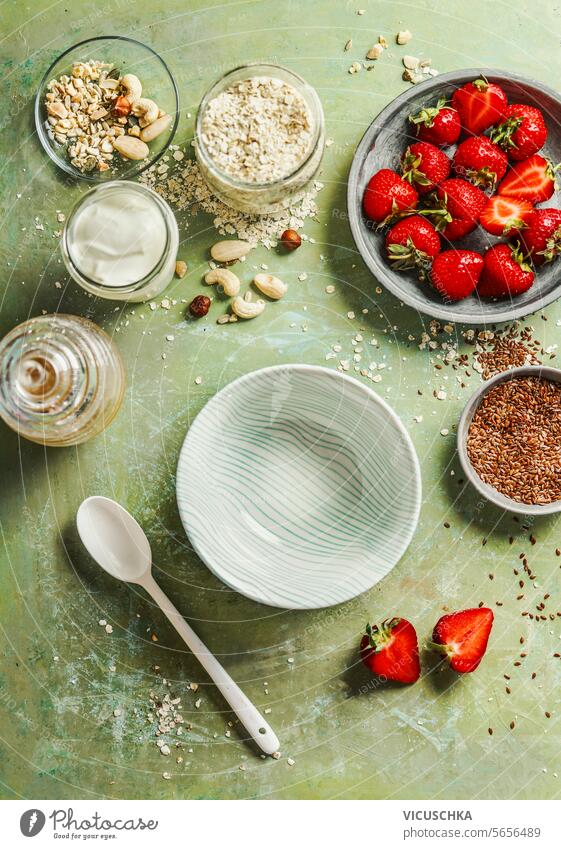 Healthy breakfast bowl preparation with oatmeal, yogurt, flax seeds,nuts and strawberries on green table background , top view healthy breakfast vegan morning