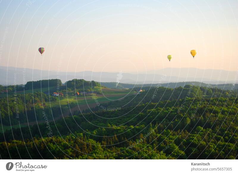 Three hot-air balloons float over the hilly landscape of Eastern Styria. Hot air balloon three Driving travel Adventure Landscape Forest meadows fields Morning