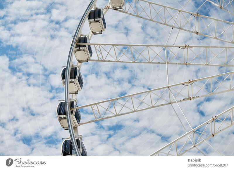 Ferris wheel rotates against background of blue cloudy sky ferris wheel attraction amusement park carousel fair fun recreation ride circle amusement ride