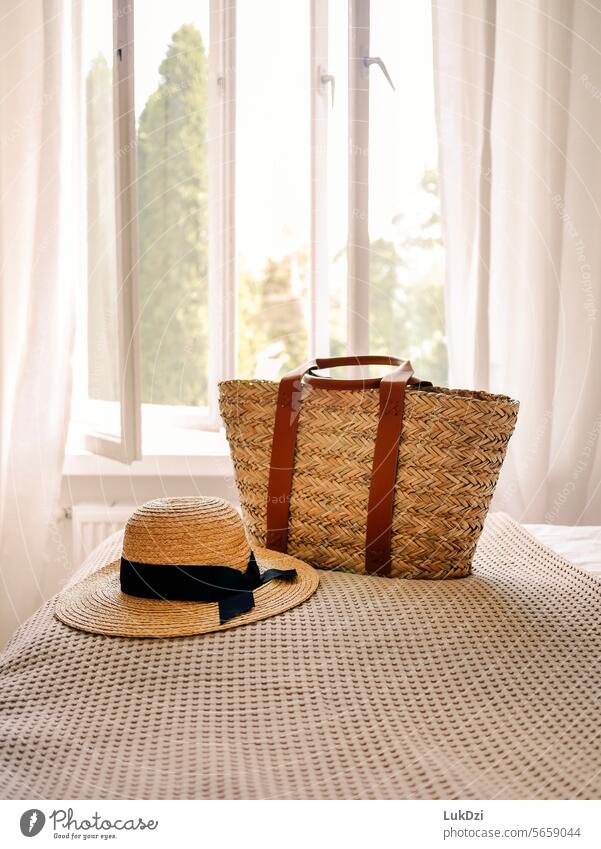 Straw hat and wicker bag on a hotel bed with an open window in the background on a sunny summer day with no people Idyll Tourism coast Hat Relaxation