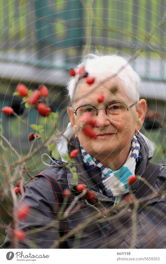 Autumn time |in search of motifs among the rose hips Nature Human being Woman looking friendly Senior citizen eye contact Looking for a photo motif see through