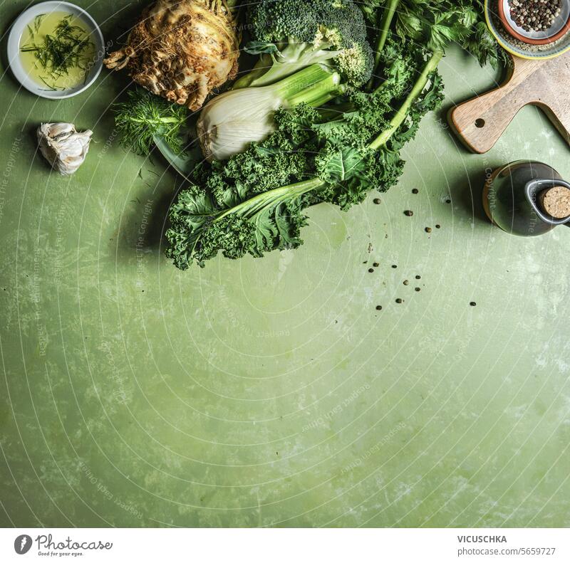 Green vegetables: broccoli, celery, fennel and kale on kitchen table with cooking ingredients, top view with copy space. Border detox food green border
