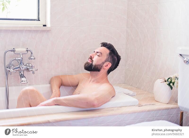 Bearded man enjoy and relaxes in bath time in beige vintage bathroom. Skin and self-care concept, men's health concept. beard hygiene shaving mens health