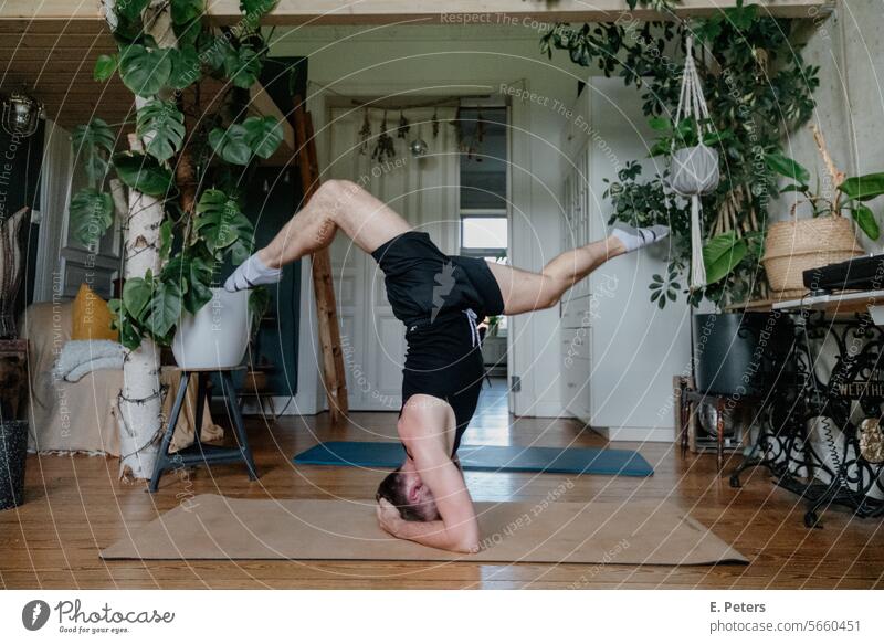 Young man doing a handstand splits in a beautiful living room on a yoga mat personal trainer Living room Fitness mat Workout workout Yoga Healthy Cozy
