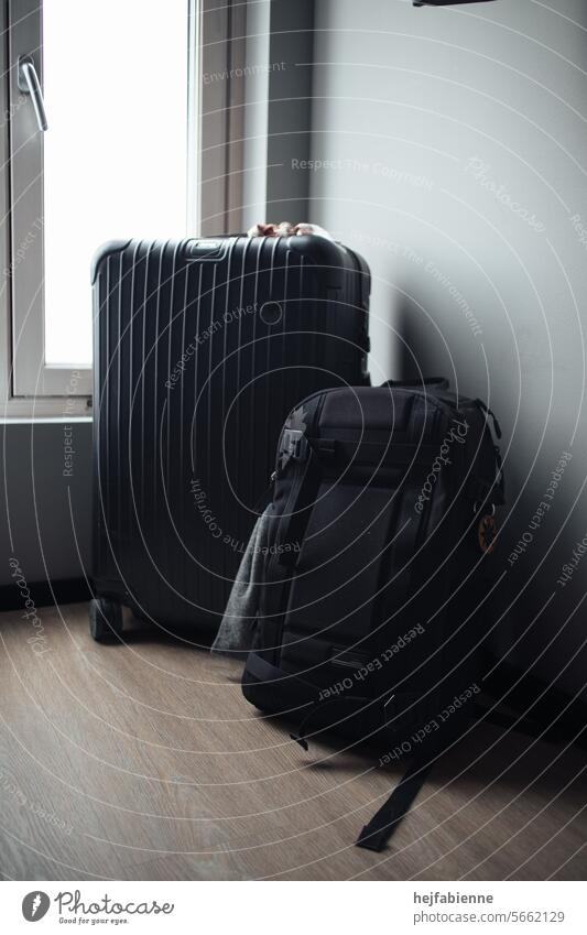 Black luggage consisting of suitcase and rucksack in hotel room Suitcase Backpack travel luggage voyage Neutral background Luggage gear Grasp be ready Adventure