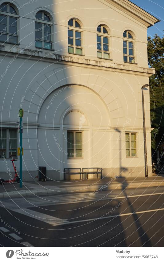 Old white building with round arch and lattice windows in the light of the evening sun with bus stop at Affentorplatz in the Sachsenhausen district of Frankfurt am Main in Hesse