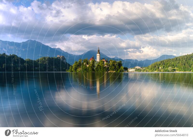 Serene waters of Lake Bled reflect the idyllic church island and castle amidst the Julian Alps on a cloudy day Slovenia reflection tranquil nature landscape