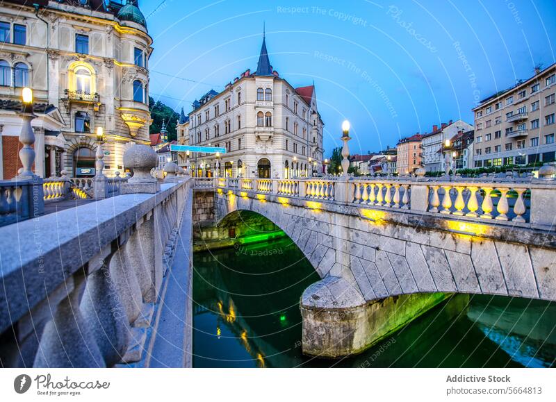 Dusk settles on the cobblestone streets of Ljubljana, with the Triple Bridge lit up and buildings reflecting on the Ljubljanica River light reflection Slovenia