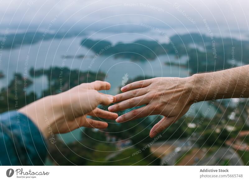 Reaching out hands above scenic lake landscape in Guatapé reach connect island high vantage point blur nature background togetherness friendship human touch