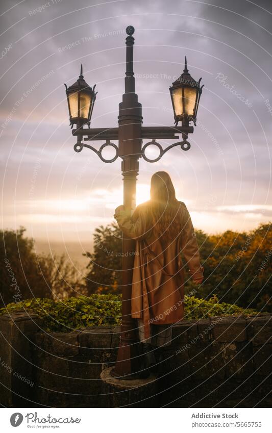 Woman by a vintage street lamp at sunset in Bogotá, Colombia woman contemplative serene background old-fashioned stand capture peaceful sky cloud outdoor dusk