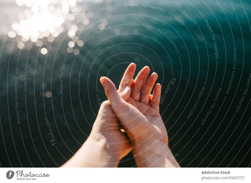 Sunlit hands over tranquil water backdrop touch sunlight sparkle gentle surface illuminated peace serene calm nature reflection simplicity connection human