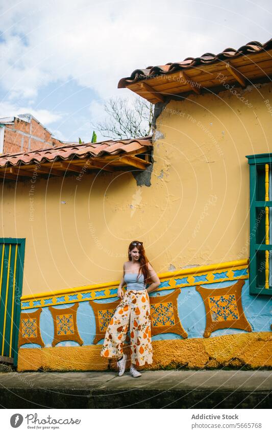 Fashionable woman posing in front of a colorful building in Guatapé fashion style traditional wall vibrant young stylish clothes leaning design element yellow