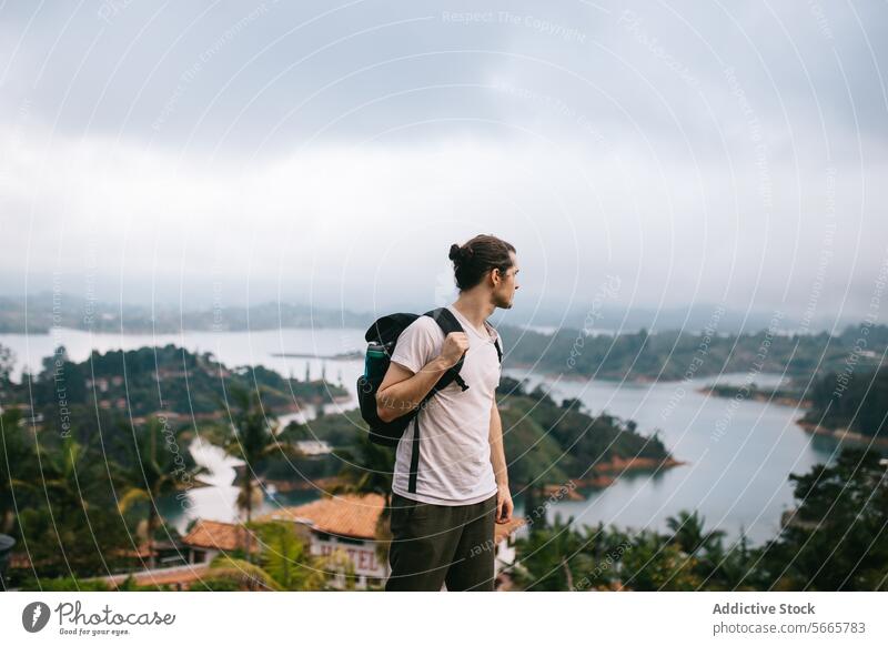 Traveler with backpack overlooking a misty lake view in Guatapé traveler landscape adventure contemplation male scenic nature outdoor exploration wanderlust