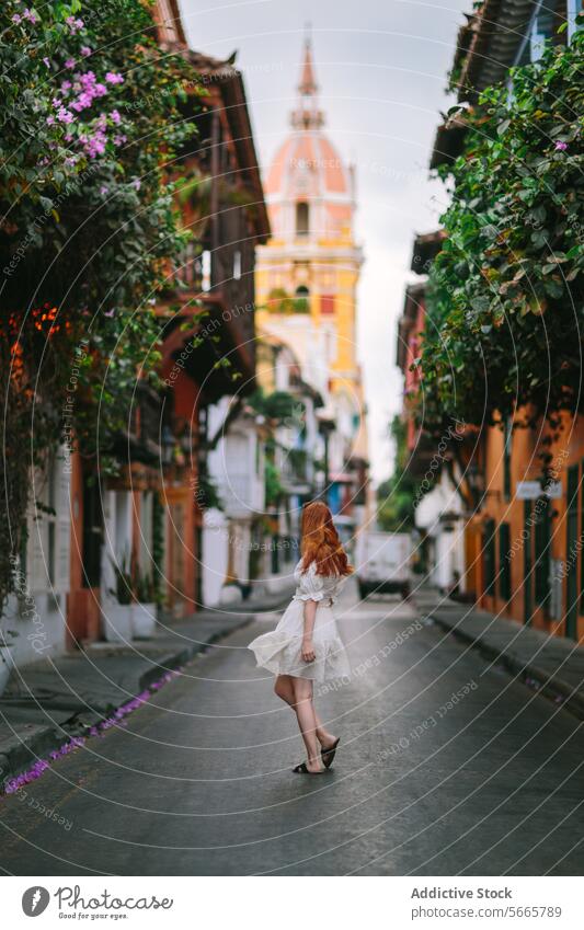 Woman Walking on a Cobblestone Street In Cartagena, Colombia woman walking cobblestone street historic town architecture colonial flowers picturesque red hair