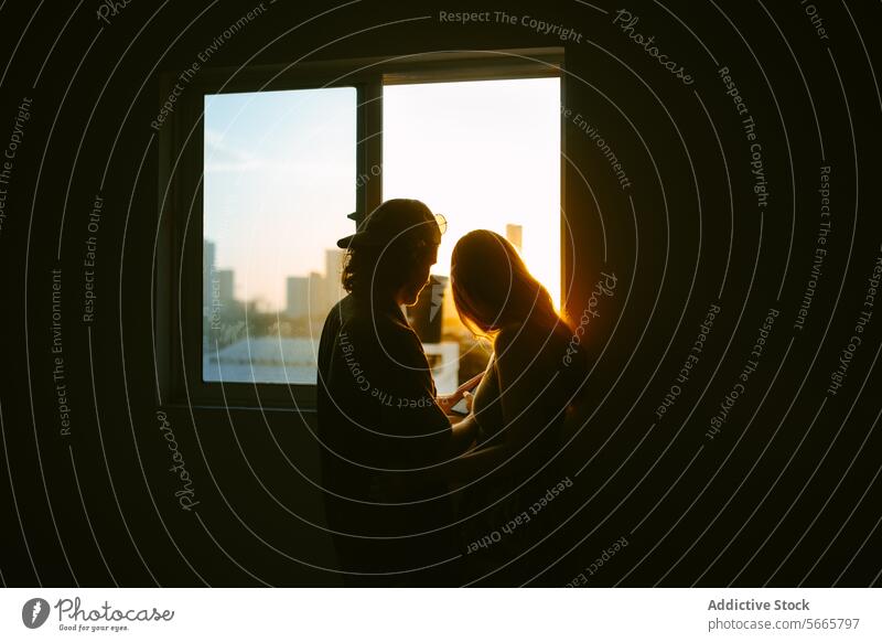 Intimate Couple Silhouetted by Sunset Through Window couple silhouette sunset window tender moment backlit warm glow intimate affection love romantic embrace