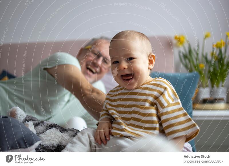 Joyful family moment with baby and grandfather smiling home cozy joy happy striped shirt playful infant elder man together bonding childhood generation casual
