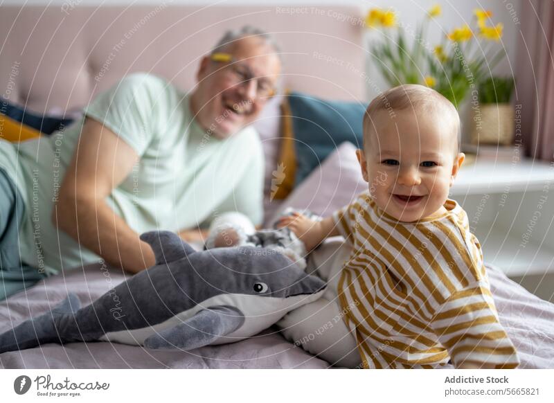 Grandfather and baby bonding with a plush toy grandfather smiling cozy bed stuffed shark joyful senior man child play laugh adorable cute family love generation