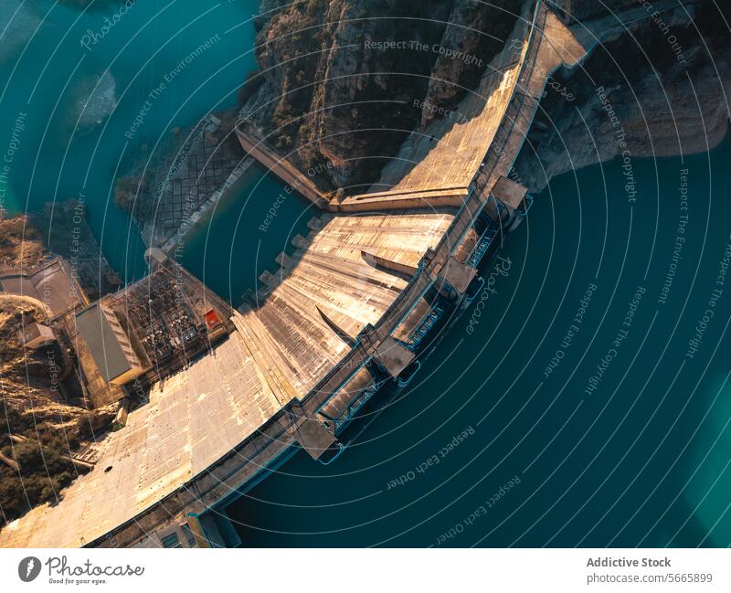 Top view of a massive dam structure with a reservoir in the mountains during clear weather hydroelectric aerial infrastructure water power engineering renewable