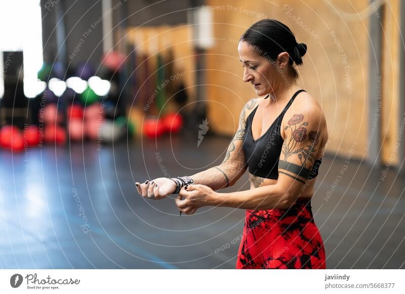 Woman protecting her wrist before training in a gym horizontal copy space mature woman protection fitness exercise preparation workout wellness health