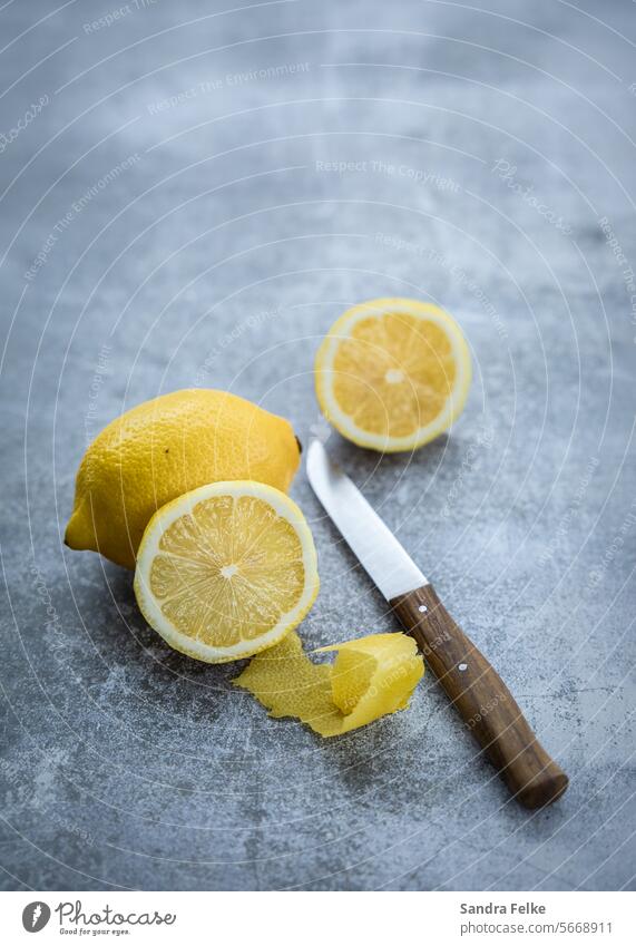 Lemons with knife on gray background Knives Fresh Food Citrus fruits naturally Healthy Yellow Fruit Nutrition Diet Vegetarian diet Juicy Vitamin Colour photo