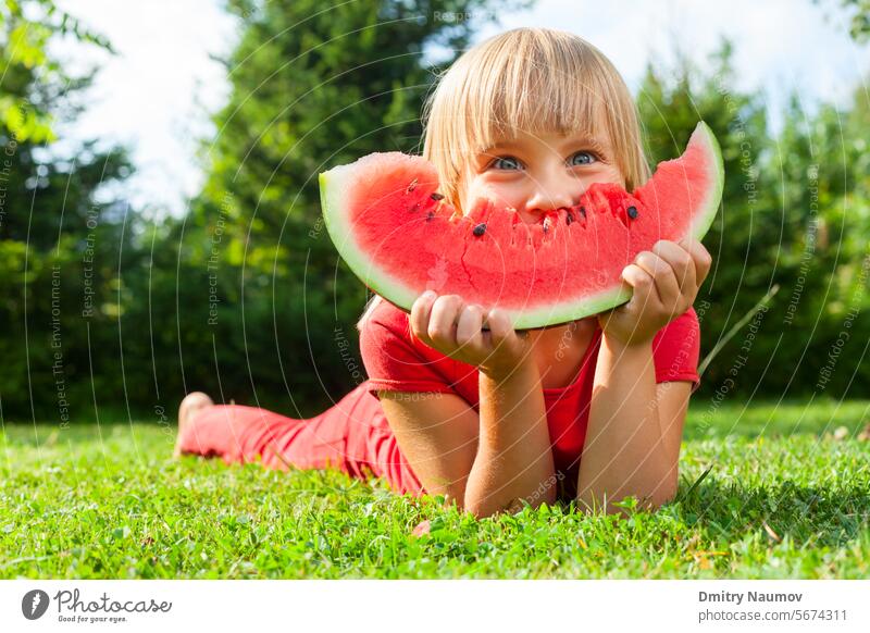 Child with slice of melon outdoor Looking At Camera appetite blonde caucasian child cute delicious dessert eat enjoying enjoyment food fresh fruit fun garden