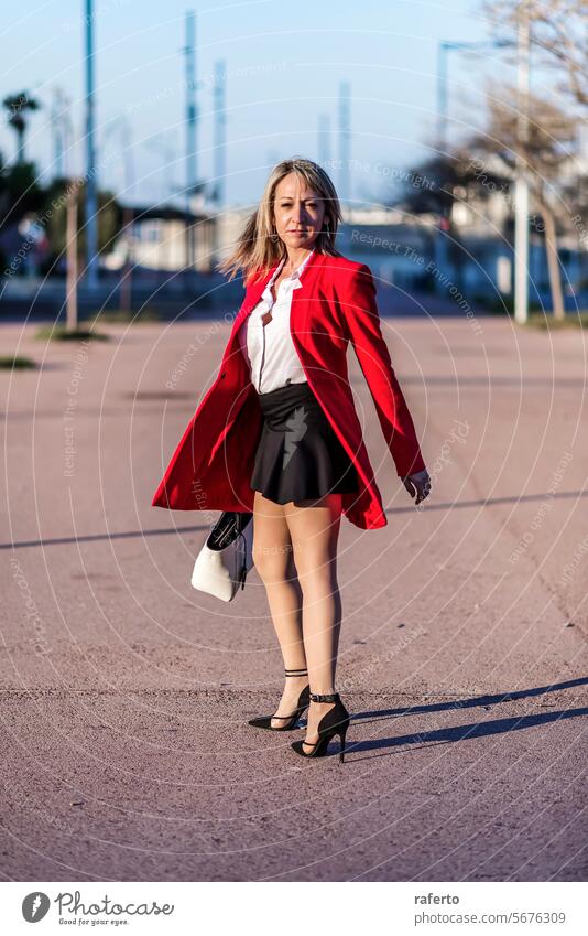 Blonde woman in red blazer standing and posing in the street business outdoors city adult female success building lifestyle professional office urban