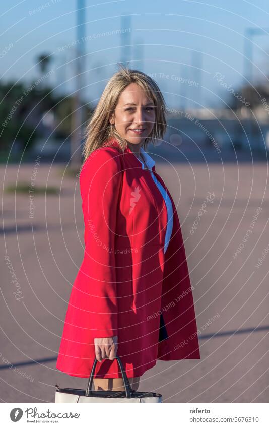 Blonde woman in red blazer standing and posing in the street business outdoors city adult female success building lifestyle professional office urban